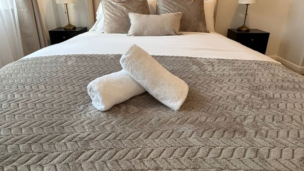 A hotel room with a large bed, two nightstands, and two wall-mounted lamps. - Central London Apartment Near Tower Bridge | Private Entrance & Garden (London)