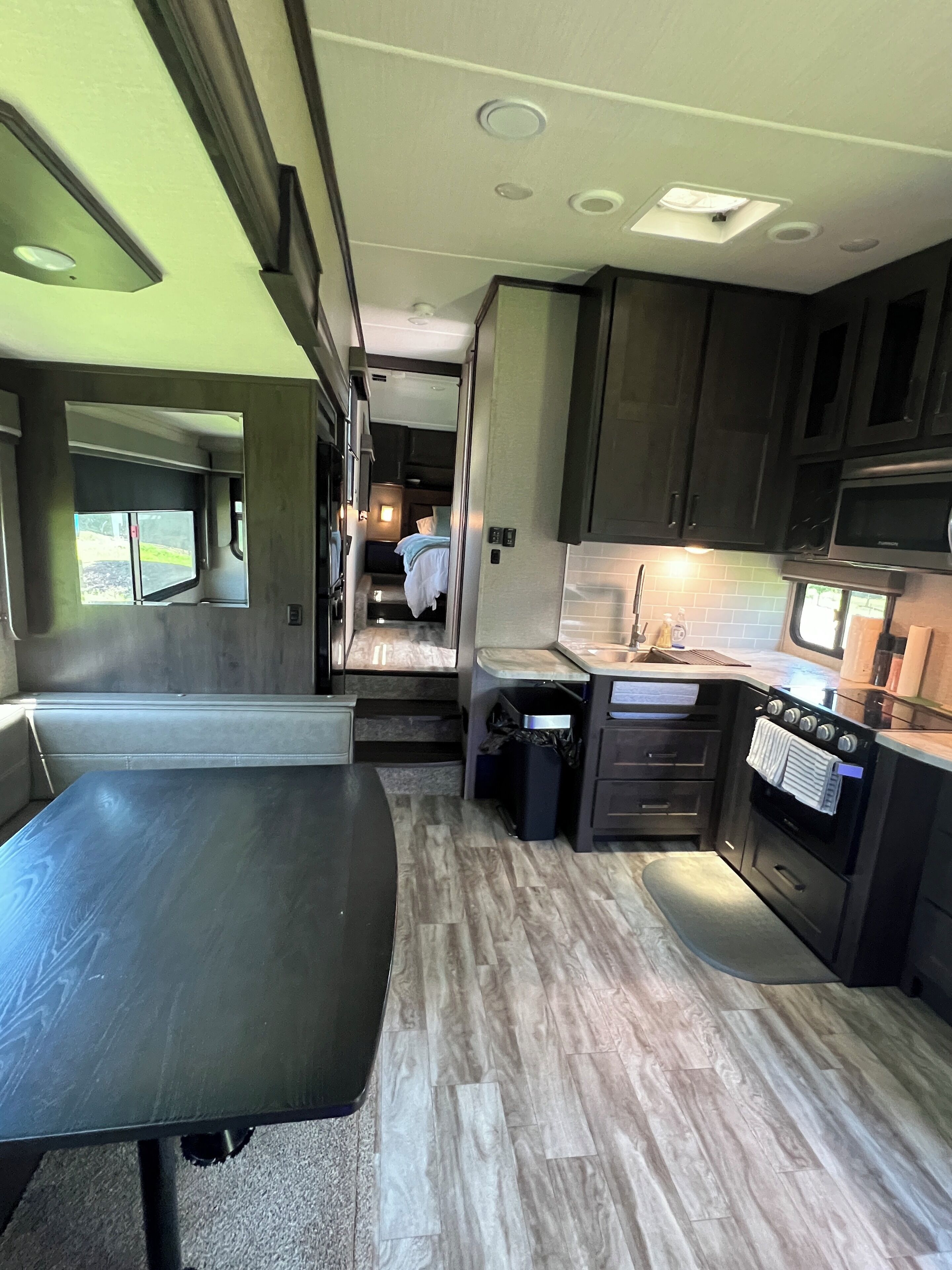 A compact RV kitchen with a dining area, built-in appliances, and a small seating space.