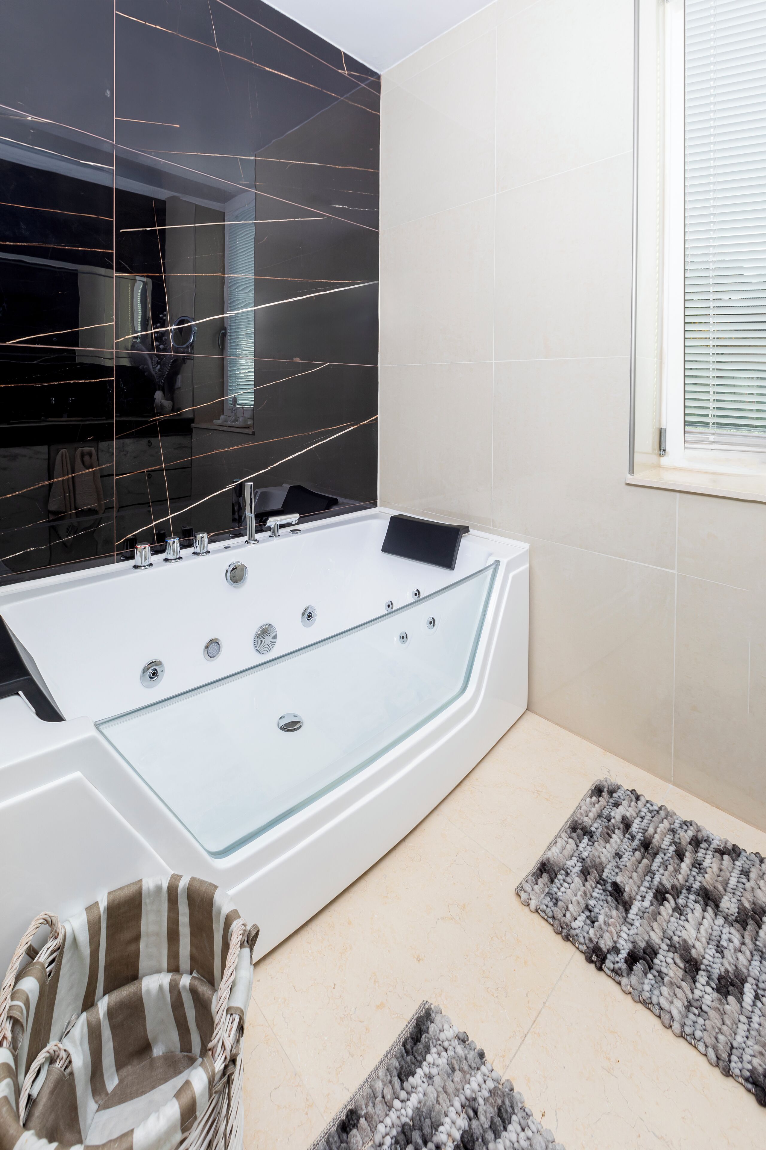 A modern bathroom with a large bathtub, a mirror, and a window.
