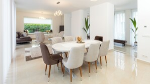 A modern dining area with a round table, six chairs, and a chandelier. - Villa Nova Berlin: Modern vacation home with plenty of space for relaxation and comfort (Berlin)