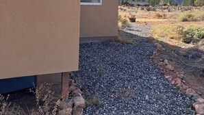 A modern house with two large windows, a gravel driveway, and a mountainous landscape in the background. - Sunny & Private I bedroom House with Sun Room for Guests (Torrey)
