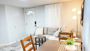 A dining area with a wooden table, chairs, a small side table, and a potted plant. - Southside City Cottage with ample parking-Sleeps 5 (Jacksonville)