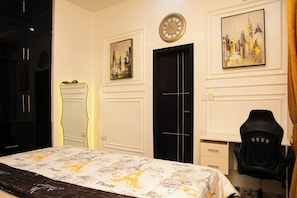 A hotel room with a bed, a black door, a round wall clock, and two framed cityscape paintings. - Luxury 2 Bedroom Bungalow with 24 hours Electricity/AC in Akobo Ibadan (Iyana Church Road, Akobo)