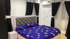 Una camera da letto con un letto, un comodino, un condizionatore d'aria a parete e tende nere.
