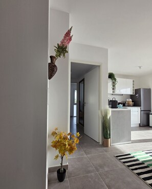Una cocina moderna con armarios blancos, un refrigerador de acero inoxidable y una zona de comedor con un tapete a rayas.
