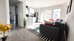 Ein modernes Wohnzimmer mit einem grauen Sofa, einem Streifenmuster-Teppich und einem Blumentopf.
