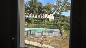 Blick durch ein Fenster auf eine Wohngegend mit Schwimmbad, eingezäunter Garten und Häuser im Hintergrund.