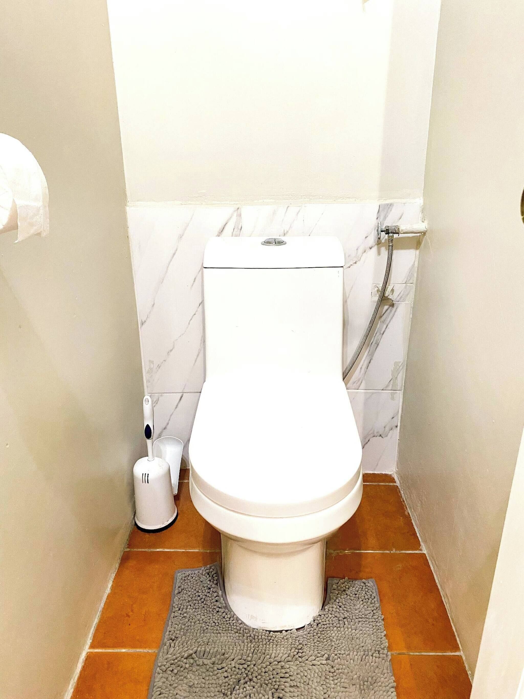A small bathroom with a toilet, a shower, and a towel rack.