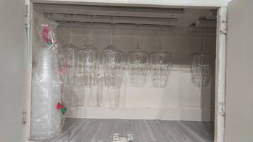 A storage cabinet with multiple wine glasses hanging from the top.