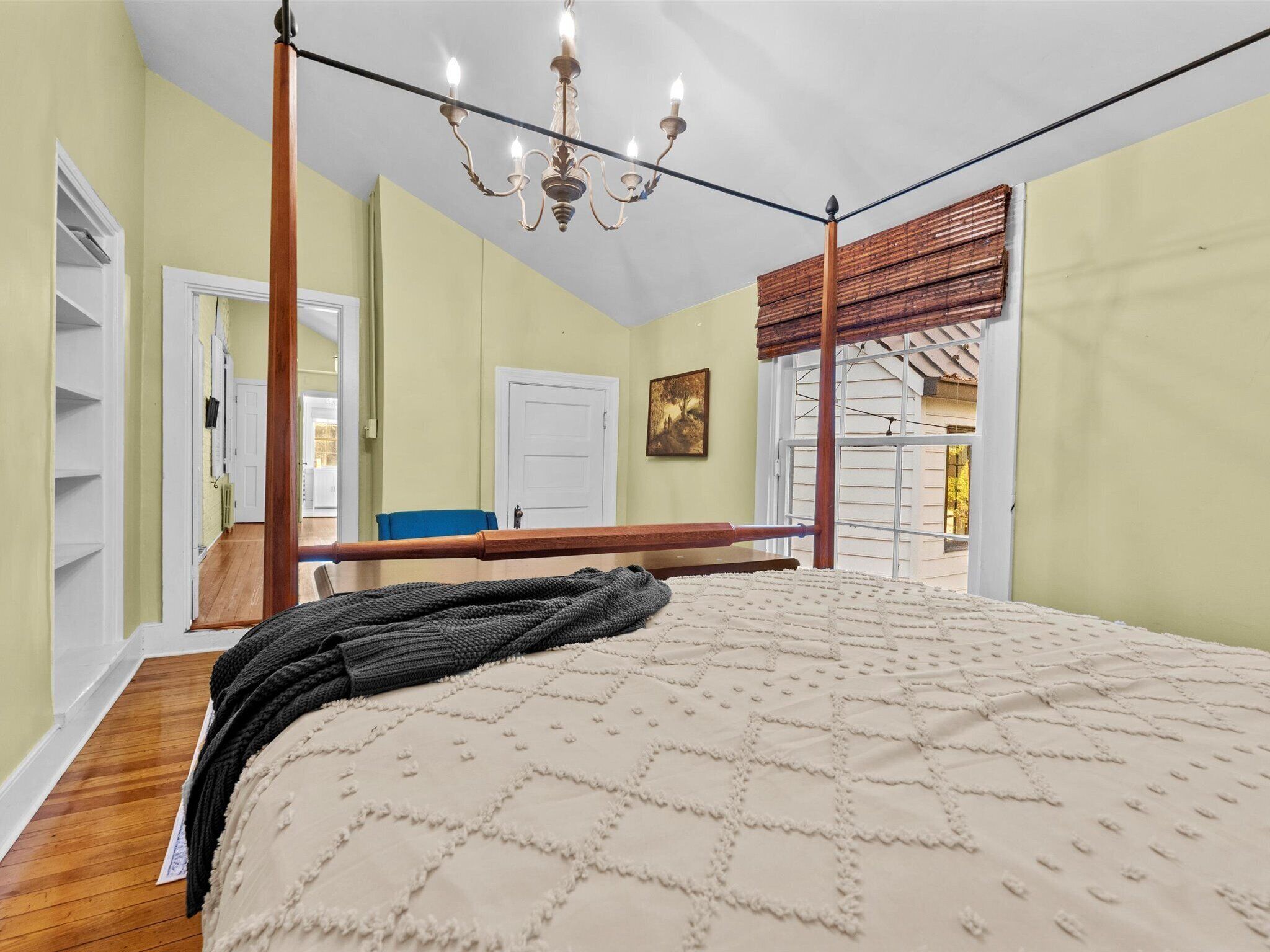 Una camera da letto con un letto a baldacchino, un lampadario e vista sull'esterno.