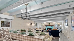 Uma sala de jantar com toalha quadriculada, cadeiras brancas e um candelabro.
