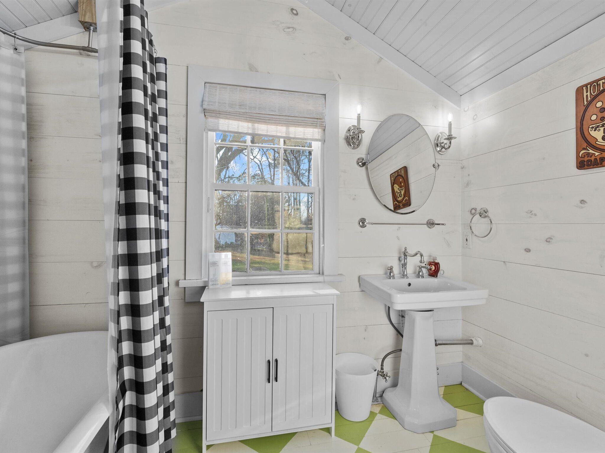 A bathroom with a bathtub, a sink, a toilet, and a window.