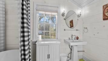 A bathroom with a bathtub, a sink, a toilet, and a window.