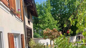 A courtyard with outdoor seating, potted plants, and a building with wooden shutters.