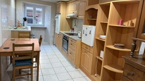 A compact kitchen with wooden cabinets, a built-in oven, a refrigerator, and a window providing natural light.