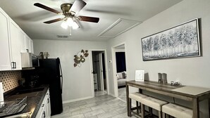 A kitchen with a ceiling fan, a dining area with a bench, and a painting on the wall.