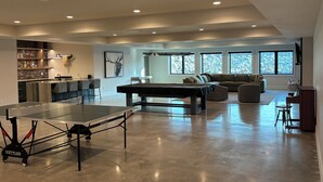 Un grand espace de vie comprenant une table de billard, un canapé et un coin bar agrémenté d’une décoration sur le thème des crânes.
