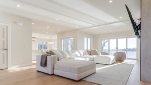 Een ruime woonkamer met een grote hoekbank, een vloerkleed en uitzicht op de omgeving.