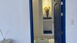 A hallway with a blue door, a white wall, a tiled floor, and a small rug. - Crete Apartment, A Mediterranean charm. (Puerto Vallarta)