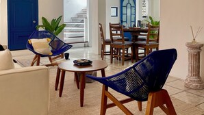 A living room with a ceiling fan, a blue door, and a dining area with wooden chairs and a table. - Crete Apartment, A Mediterranean charm. (Puerto Vallarta)