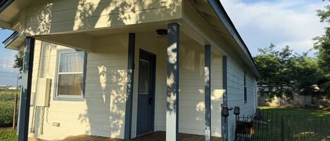 A single-story house with a front porch, a door, and a window.