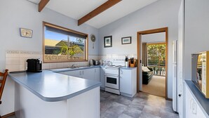 Una cucina moderna con mobili bianchi, isola integrata e un'ampia finestra.