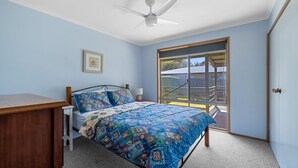 Una camera da letto con un letto, una scrivania, una ventola a soffitto, una finestra e una porta.