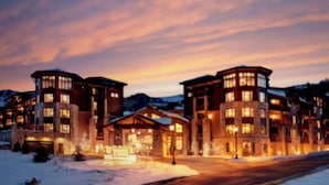 Un hotel con varias construcciones, suelo cubierto de nieve y montañas al fondo.