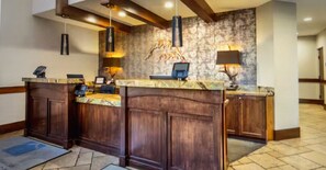 A reception area with a marble counter, wooden paneling, a stone wall with a decorative fish mural, and a hanging light fixture. - PRESIDENTS WEEK: Feb 14-21, 2026 “SKI IN” HILTON: SUNRISE LODGE  3-bedroom Condo (Park City)