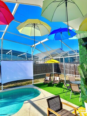 Ein überdachter Außenbereich mit Pool, Liegestühlen und Sonnenschirmen.