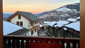 Blick auf ein verschneites Dorf mit traditionellen Häusern und einem Berg im Hintergrund.
