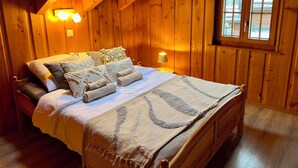 Ein gemütliches Zimmer mit Holzboden, einem Bett, einem Nachttisch und einem Fenster.