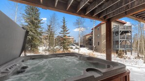 Uma banheira de hidromassagem com vista para uma paisagem nevada e edifícios ao fundo.