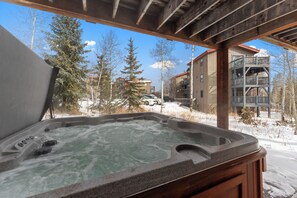 A hot tub with a view of a snowy landscape and buildings in the background. - 40bcs3 (Silverthorne)