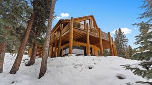 A wooden cabin with a balcony, surrounded by snow-covered ground and trees. - 14mcbr3 (Breckenridge)