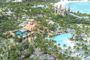 Eine Luftaufnahme eines Resorts mit mehreren Schwimmbecken, Palmen und einer großen Wasserpark-Anlage.