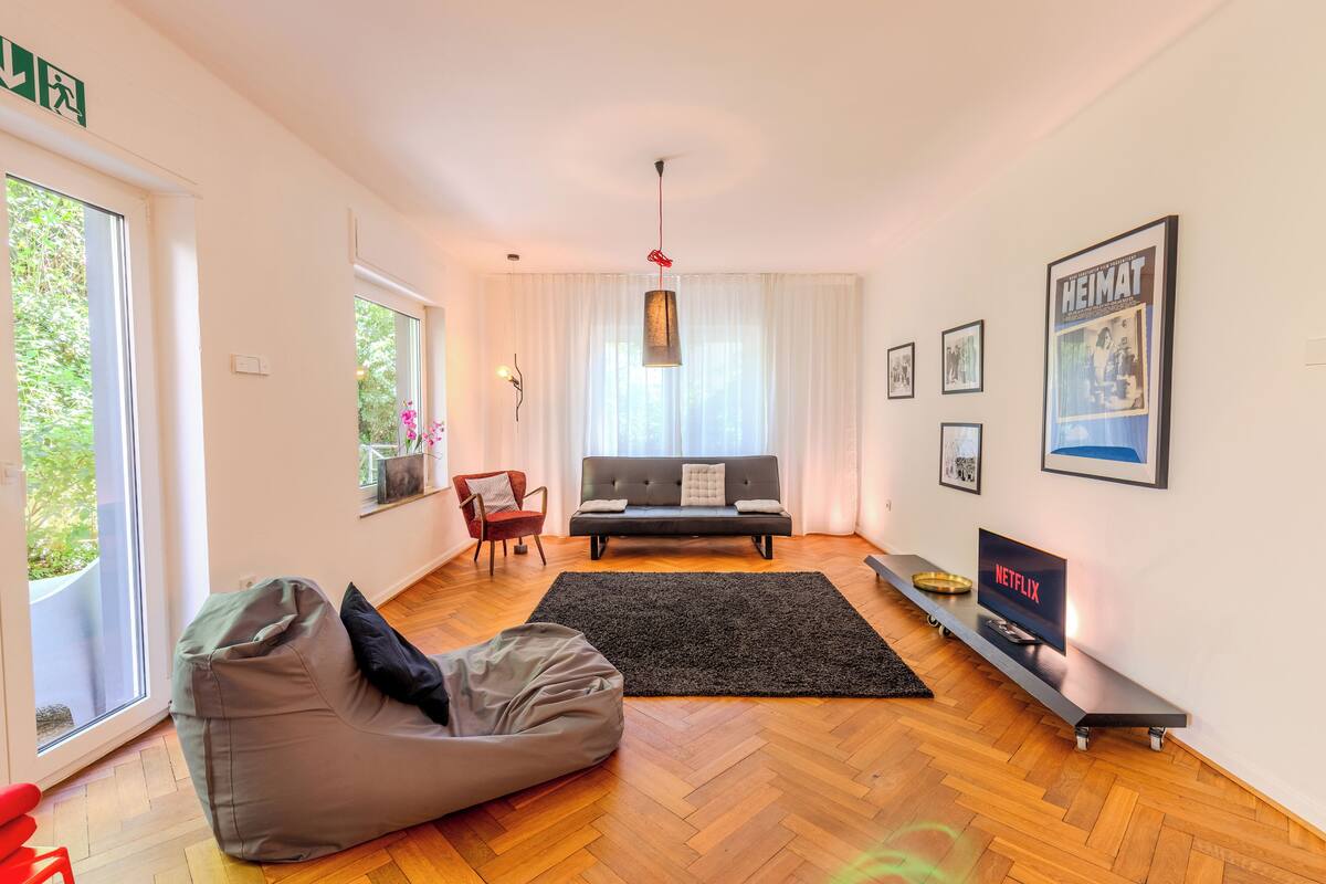 Un salon moderne avec un canapé, un fauteuil poire, un téléviseur et des œuvres d’art accrochées aux murs.