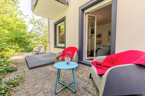 An outdoor seating area with a table, chairs, and a covered sofa. - Soon Apartments by corents (Simmern)