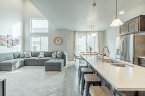 A modern kitchen with a large island, stainless steel appliances, and a dining area with bar stools.