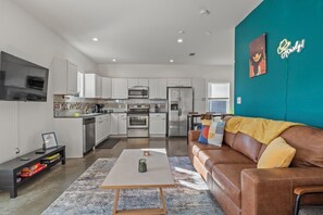 Een moderne keuken met witte kasten, roestvrijstalen apparatuur en een wand in een blauwgroene kleur.