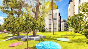 Un patio bien cuidado con césped, árboles y zonas de estar circulares.