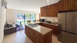 Una cocina moderna con una isla central, armarios de madera, estufa integrada y un refrigerador grande.