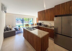 A modern kitchen with a central island, wooden cabinets, a built-in stove, and a large refrigerator. - Apartment in front of the swimming pool, security, 24 h security (Puerto Vallarta)
