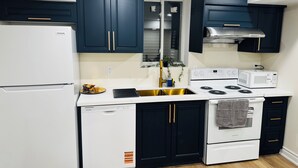 Una cocina moderna con armarios oscuros, electrodomésticos blancos y un lavamanos de acero inoxidable.