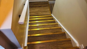 Una escalera de madera con barandilla y un rellano cubierto de alfombra oscura.
