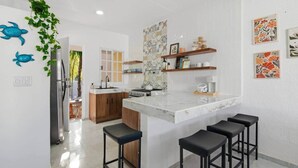 Cozinha moderna com ilha central, banquetas e decoração de parede.