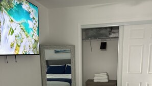 Une chambre à coucher avec un lit, une télévision, une armoire et un miroir.