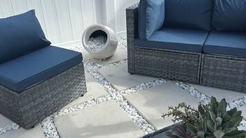A patio with two dark blue cushioned sofas, a stone planter with a succulent, and a concrete planter with white pebbles.