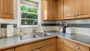 Una cocina con armarios de madera, un lavamanos doble, una ventana y una encimera con un tostador y una licuadora.