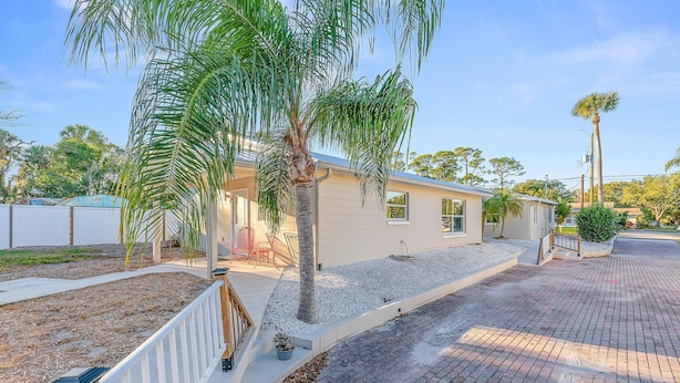 Propiedad residencial con camino de entrada pavimentado, palmeras y patio cercado.